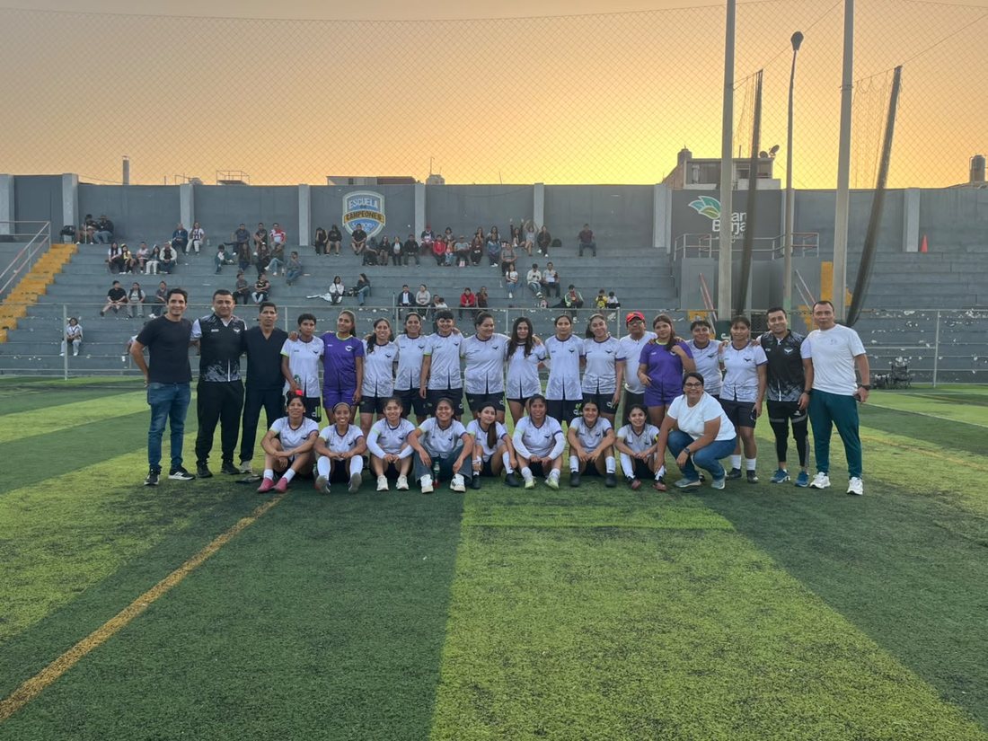 Equipo femenino posando en el estadio al atardecer